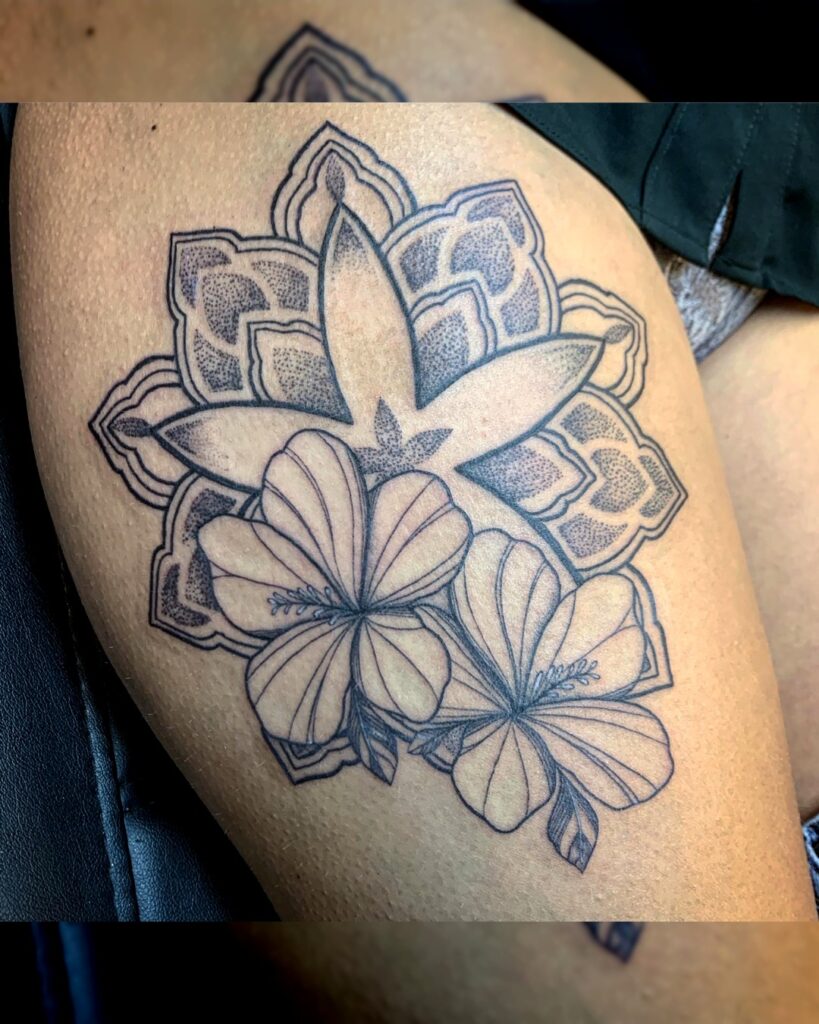 Tattoo van mandalapatroon met hibiscusbloemen in lijn- en dotworkstijl op het bovenbeen, gezet bij Tat2holics in Den Haag