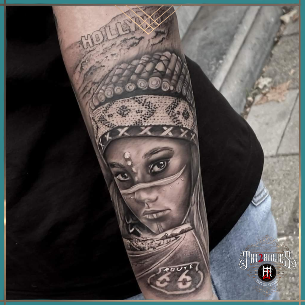 Realistische tattoo van een vrouwelijk portret met tribale hoofdtooi en Route 66 symbool op de onderarm