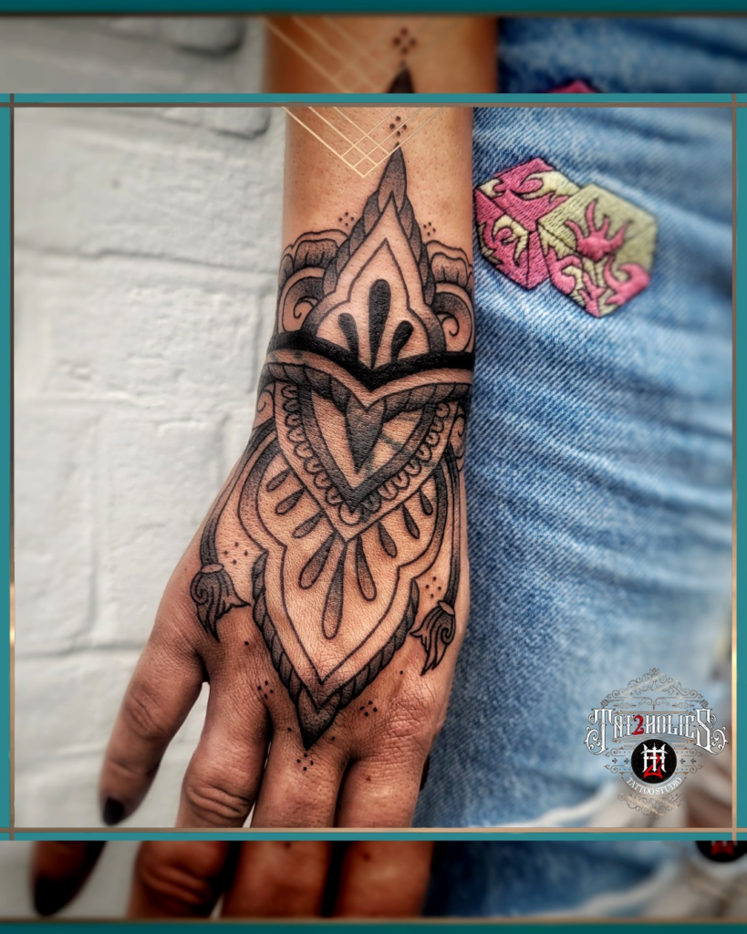 Symmetrische mandala tattoo op de hand, met dikke fineline accenten en ornamentale details, geplaatst door Tat2holics in Den Haag
