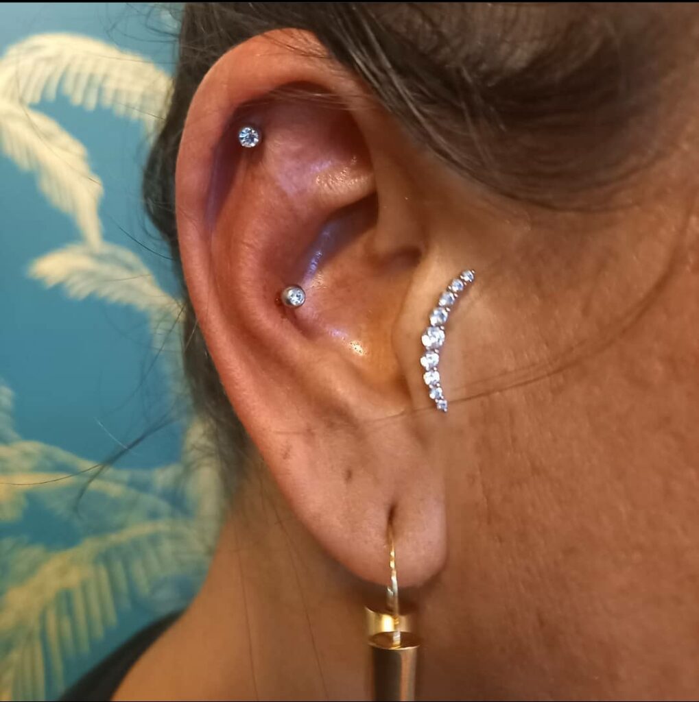 Oor met meerdere piercings en sierlijke steentjes, gezet bij Tat2holics in Den Haag