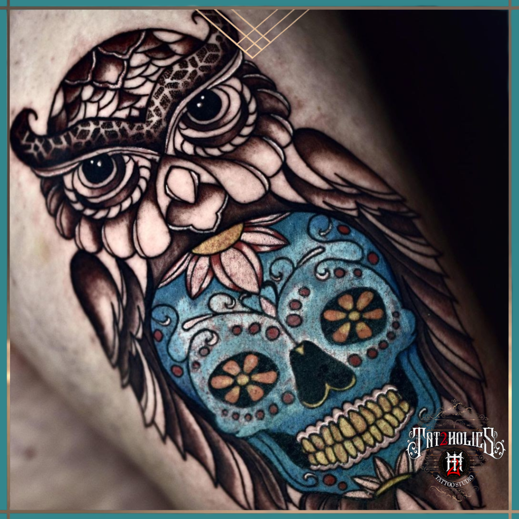 Tattoo van een realistische uil gecombineerd met een blauwe Mexicaanse sugar skull, versierd met bloemen en patronen, geplaatst bij Tat2holics in Den Haag