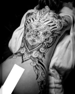 Blackwork tattoo over de volledige rug met mandala’s, bloemen en sierlijke lijnen, symmetrisch en gedetailleerd uitgevoerd bij Tat2holics in Den Haag