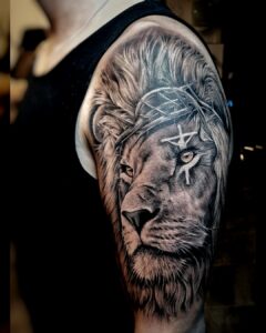 Gedetailleerde bovenarmtattoo van een leeuw met doornkroon en symbolische witte markeringen