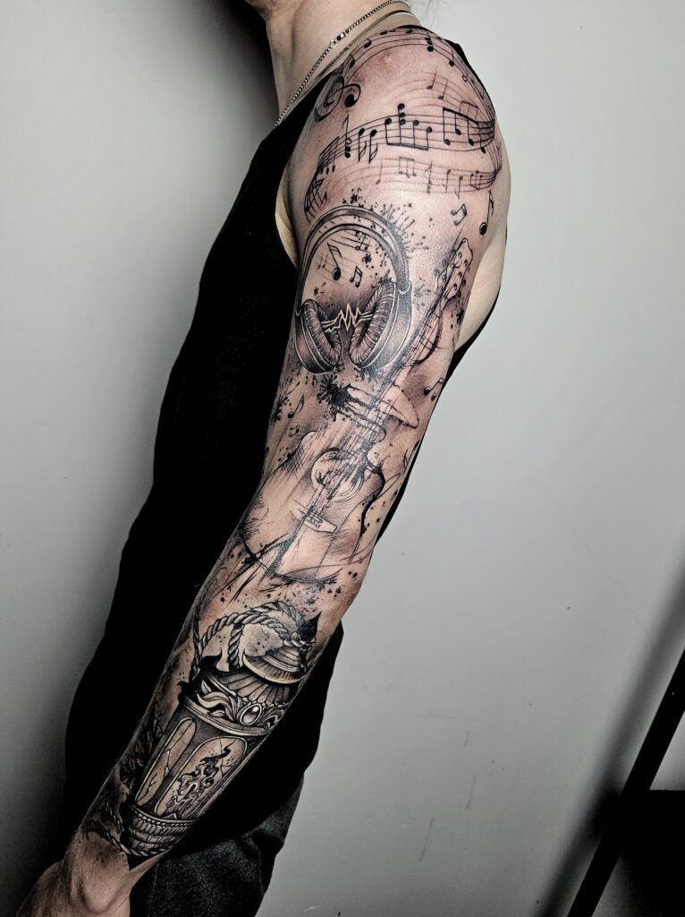 Volledige armsleeve tattoo met muzikale elementen zoals notenbalken, koptelefoon, viool en klok, gezet in realistische stijl