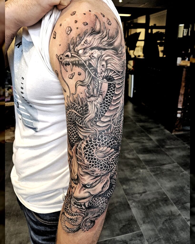 Volledige armtattoo van een Japanse draak in zwart-grijs stijl, met dynamische schubben en intense expressie