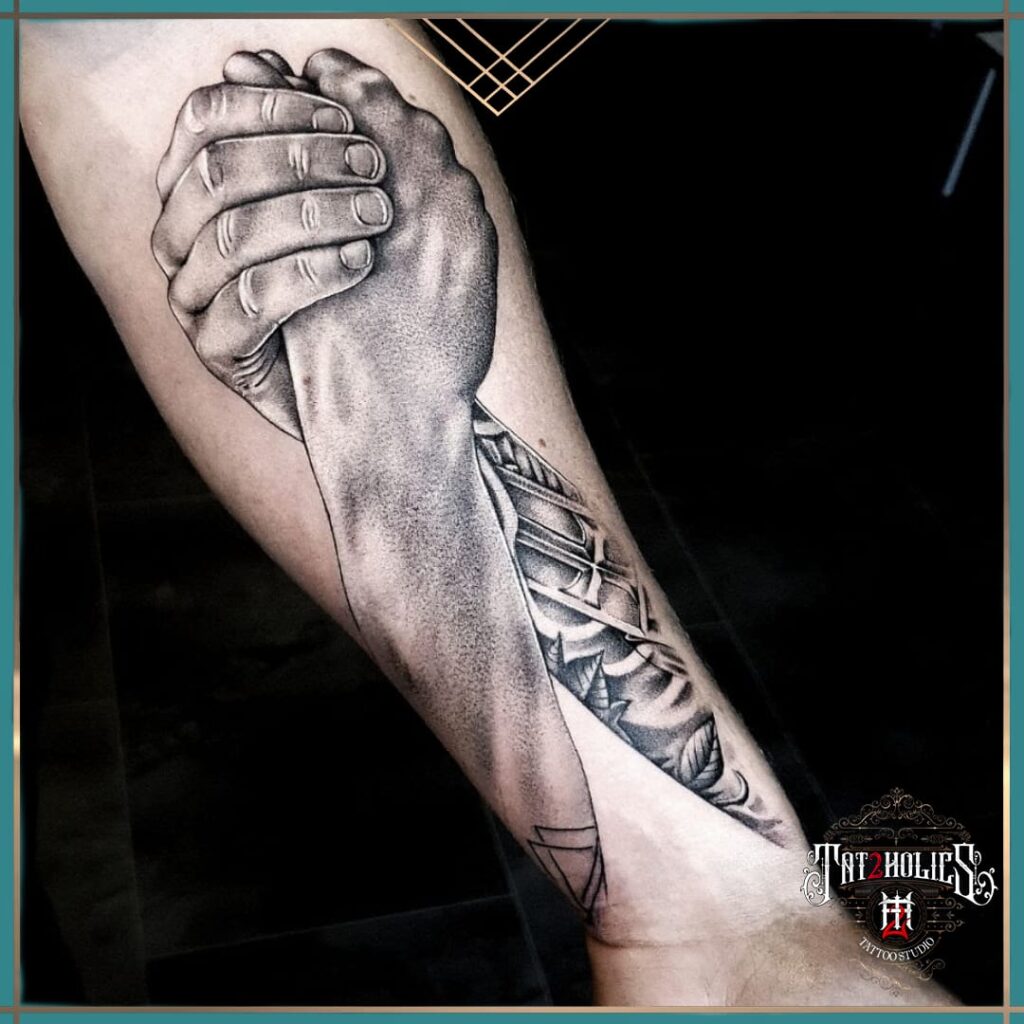 Zwart-grijze tattoo van twee ineengrijpende handen, met realistische schaduwtechniek en geometrisch patroon