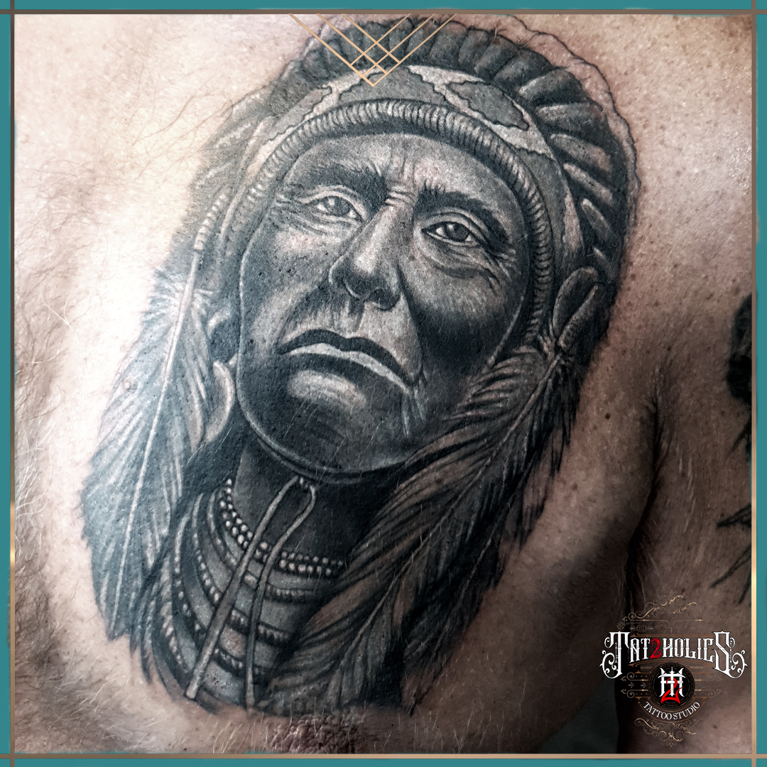 Tattoo van een Native American leider met hoofdtooi en kralenketting, realistisch uitgevoerd op de borst bij Tat2holics in Den Haag
