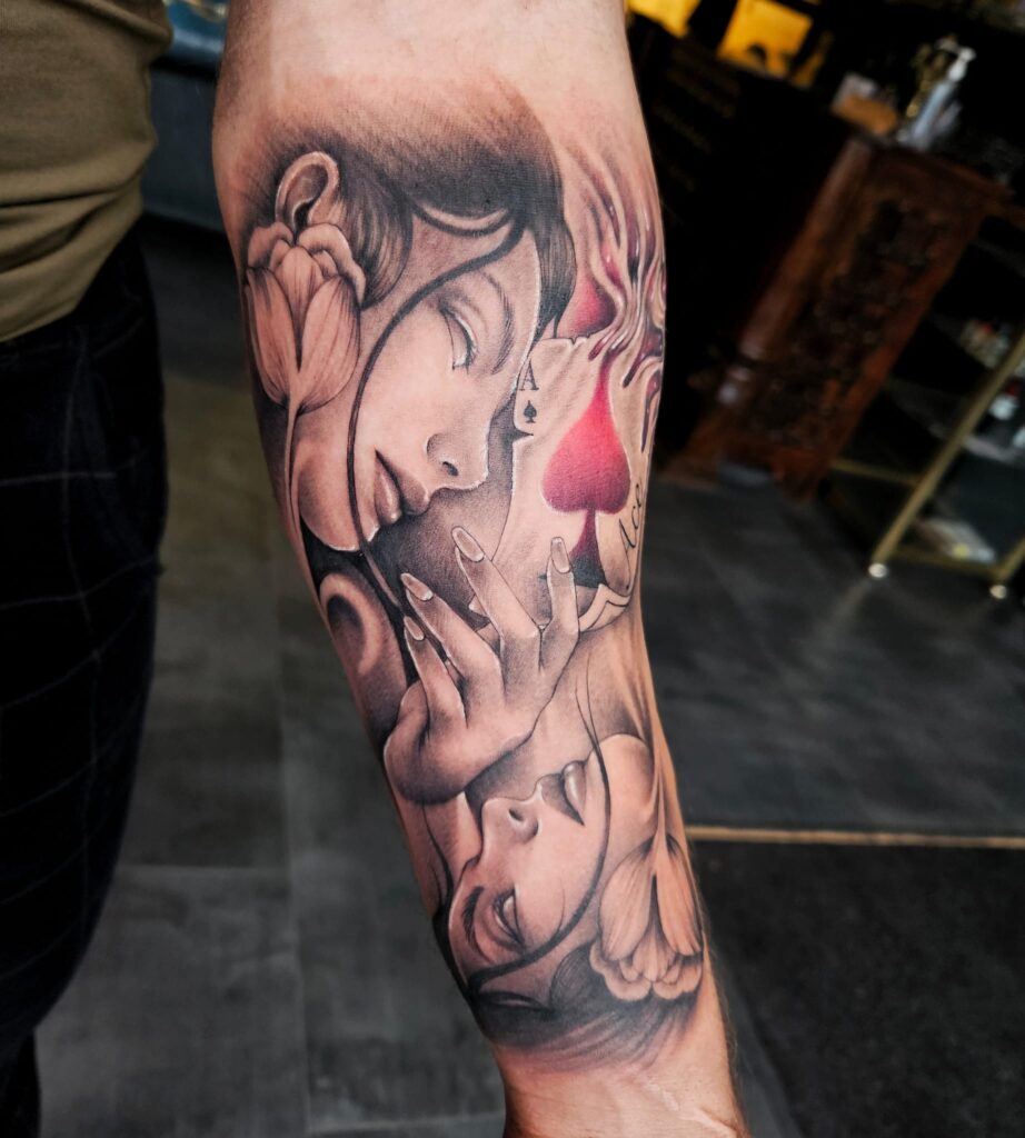 Tattoo op onderarm in manga-realistische stijl met vrouwelijke gezichten en speelkaartdetails