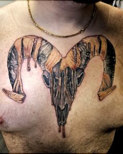 Tattoo van een verweerde ramsschedel met druipend effect, geplaatst prominent op de borst